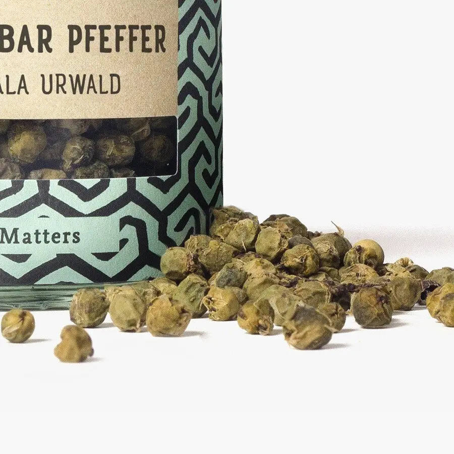 Grüner Malabar Pfeffer Nahaufnahme von Glas und Pfefferkörnern