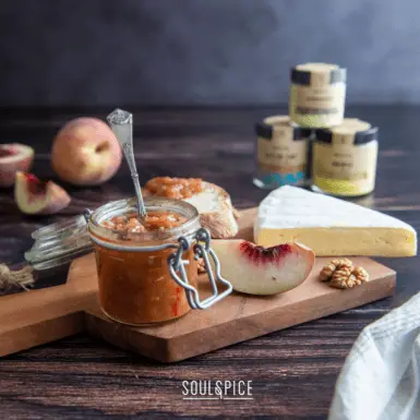 Pfirsich Chutney auf Holzrett mit Brie, Brot und Pfirsichen